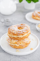 French traditional cake Paris Brest with praline cream, powdered sugar and almond petals on top on a gray concrete background. Copy space.