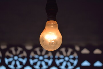 Hanging incandescent light bulb a dark place
