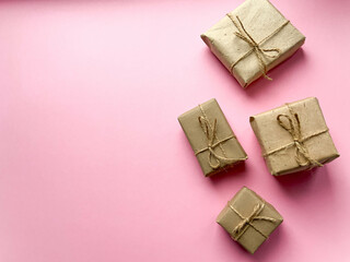 A gift box wrapped in kraft paper on a pink background. View from above, flat lay, top view design. Minimalism. Concept sales, shopping, christmas holidays and birthday.