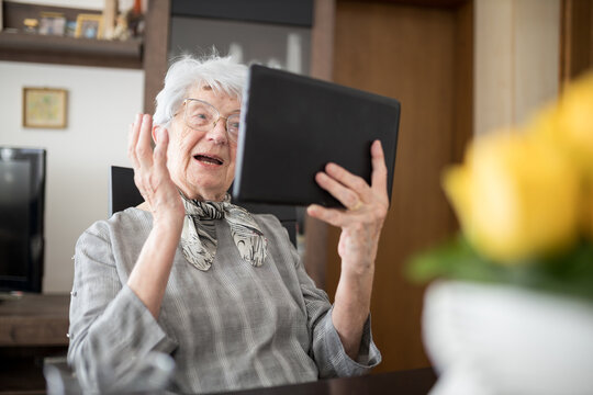Serious senior Caucasian woman having a video conference call in her living room. Loneliness and aging concept