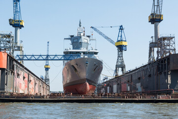 military ship repaired in a dry dock - obrazy, fototapety, plakaty