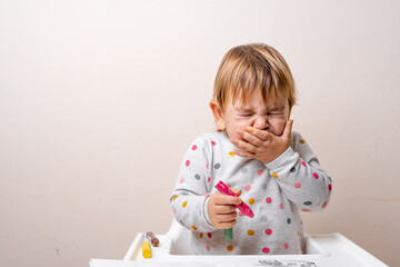 Toddler child sneezing while drying with crayons. Baby with allergy or cold from daycare or...