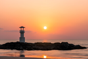 Khao Lak light beacon or lighthouse for navigation on rock near beach during sunset, famous travel...