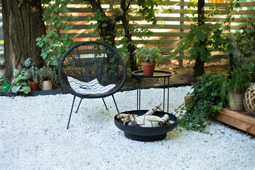 Outdoor patio furniture on pebbles in a front garden. Front veranda of house with two black...