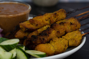Satay is skewered meat on a bamboo stick then grilled on charcoal fire eaten with peanut gravy. Satay is a famous street food in South East Asia. Selective focus