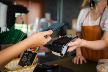 Paying with Mobile Phone,Mobile payment,customer pays a bill payment via a smartphone using NFC technology in a cafe.
