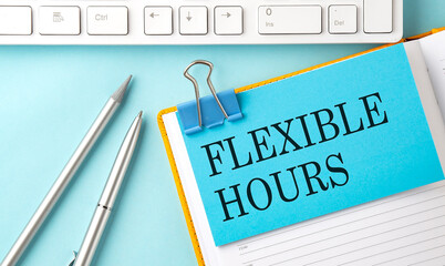 FLEXIBLE HOURS text on sticker on the blue background with pen and keyboard