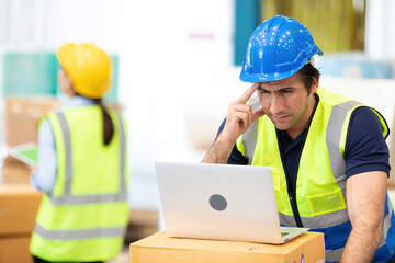 engineer or factory worker using laptop computer and thinking of something seriously in warehouse storage