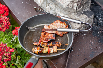 Delicious grilled meat in the cast iron grill pan with a variety of grilled vegetables skewers