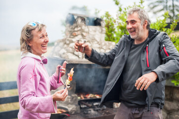 BBQ grilling party. Happy friends having a backyard barbecue party, grilling meat, drinking and relaxing on a sunny day outdoors