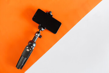 Mobile phone on a tripod with a clear display for color paper background.