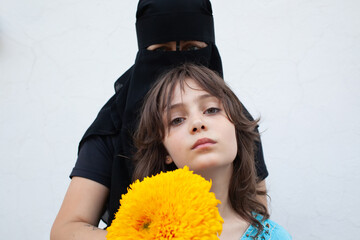 Portrait of a woman in a niqab and a little girl with yellow flower