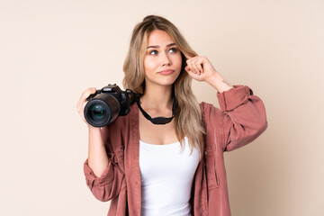 Young photographer girl over isolated background having doubts and thinking