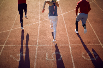 Back view of sport  people  in starting position for running on race track in stadium