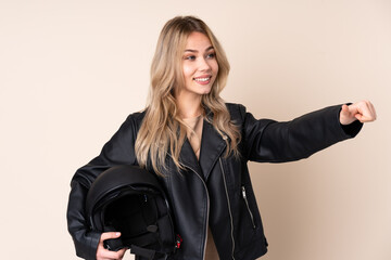 Russian girl with a motorcycle helmet isolated on beige background giving a thumbs up gesture