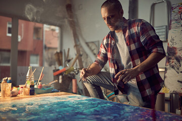 Fototapeta na wymiar Focused male painter artist creating a new piece