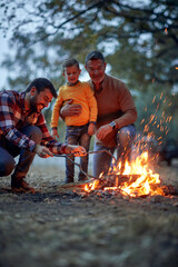 Grandfather, father and grandson lighting up a campfire in the forest