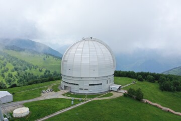 Obraz premium Nizhny Arkhyz, Russia - June 26, 2021: Aerial view of Astrophysical observatory of the Russian Academy of Sciences in Caucasus. BTA tower. Cloudy. Scenic landscape, cosmos, astronomy concept. Summer