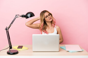 Young student woman in a workplace with a laptop over pink background with neckache