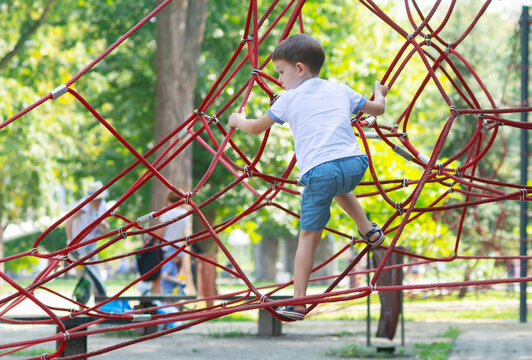 Boy climbing the ropes in the playground - Powered by Adobe