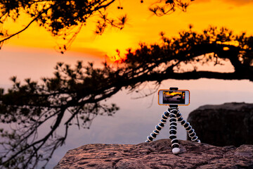 smart phone, cell phone take on mini tripod take a photo and timelapse of beautiful sunset time...