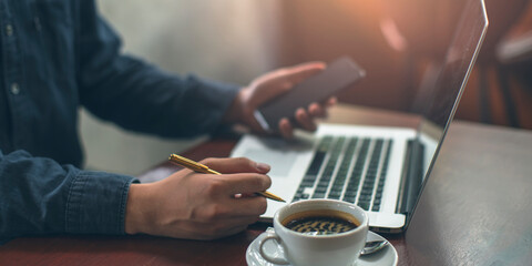 Businessman is working on Laptop and smartphone in restaurant or coffee shop. stock business or work from home concept. vintage tone