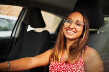 Fototapeta na wymiar Young brunette spanish woman sitting on car smiling at camera