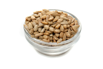 Peeled sunflower seeds in a transparent bowl on a white background.