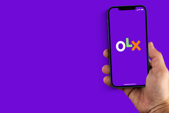 Male hand holding a smartphone with OLX App on the screen. Purple background. Rio de Janeiro, RJ, Brazil. August 2021.