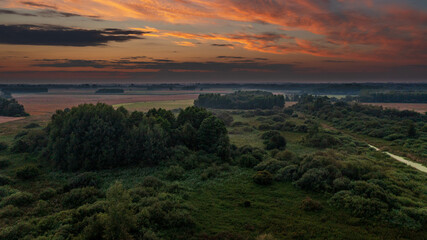 Colorful sunset over forest and fields aerial
