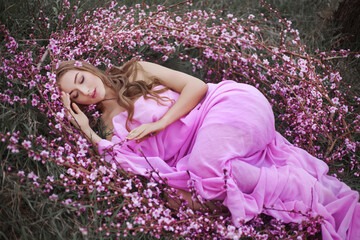 Girl in a pink flowered garden of peaches in a pink dress and makeup