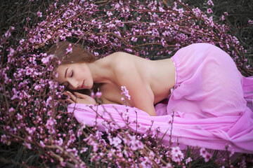 Girl in a pink flowered garden of peaches in a pink dress and makeup