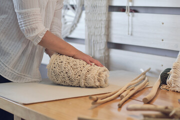 woman entrepreneur packs a handmade product in a cardboard box. delivery of goods for a small business. an elderly woman earns her hobby from home.
