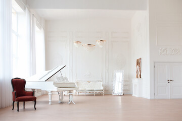 Rich luxury interior of a classic style room with vintage furniture, big windows, mirror, chandeliers and grand piano.