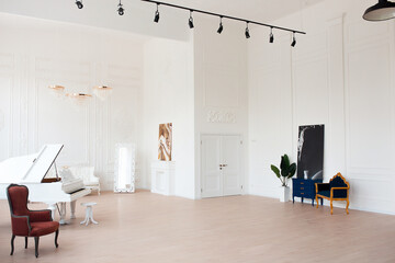 Rich luxury interior of a classic style room with vintage furniture, big windows, mirror, chandeliers and grand piano.