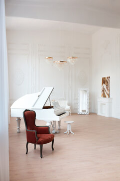 Rich luxury interior of a classic style room with vintage furniture, big windows, mirror, chandeliers and grand piano.