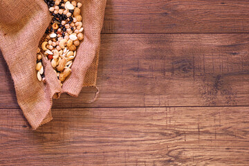 Cloth bag with nuts, legumes and seeds for vegans and vegetarians on an oak wood table.