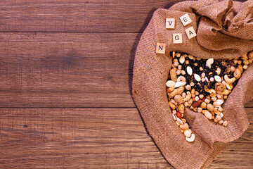 Cloth bag with nuts, legumes and seeds for vegans and vegetarians on an oak wood table.