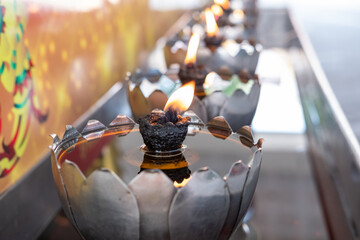 Obraz premium Burning yellow candle flame, Oil filling in Thai style metal candle in the Buddhist temple