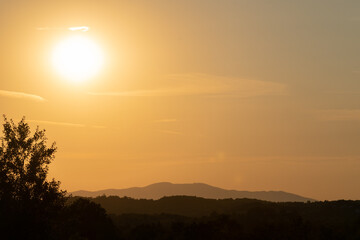 Landscape with silhouettes of layers of hills during the evening with the sun in the sky
