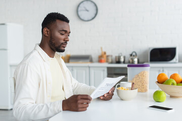 african american man reading newspaper during breakfast