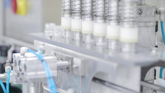 Factory worker operates bottling machinery on the production line. 