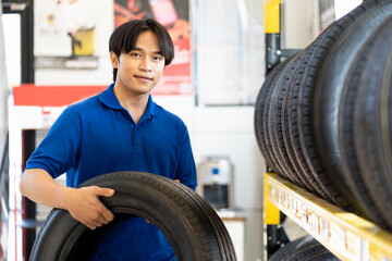 Car service. Asian male technician worker checking new tire wheel on shelves shelf at wheel store....