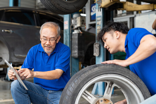 Male car mechanic worker checking, repair and maintenance wheel at auto repair shop. Group of  mechanic vehicle service maintenance examining wheel tire at garage. Auto car repair service