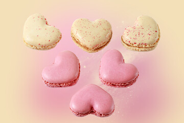 Sweet macarons in heart shape flying  on pink yellow blurred background. French macaron cookies with raspberry and vanilla.