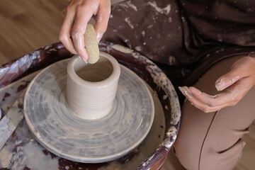 Woman hands working on pottery wheel and making a pot. Young woman making pottery on the wheel. sculpts pot from clay.