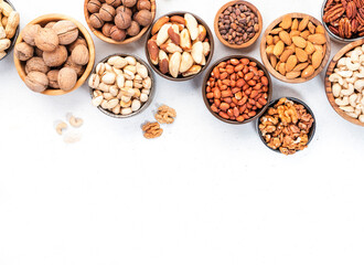Nuts in bowls. Almonds, hazelnuts, walnuts and other. Healthy food snack mix on white table, top view, copy space