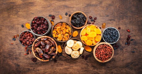 Obraz na płótnie Canvas Dried fruits bowl. Healthy food snack: sun dried organic mix of apricots, figs, raisins, dates and other on wooden table, top view