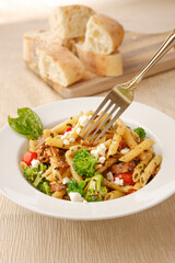 Using a fork on the penne pasta.