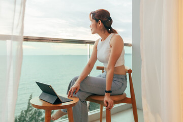 Beautiful Asian woman enjoy looking the sea view from the balcony of the hotel.